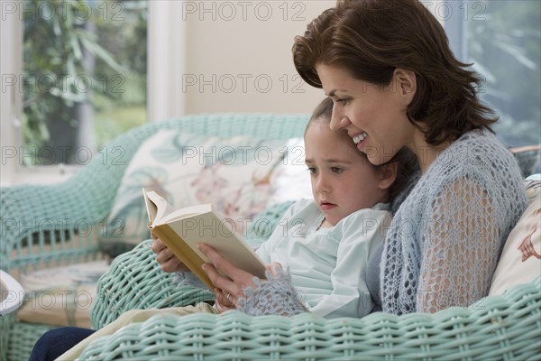 Mother reading to young daughter .