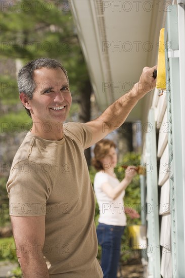 Man painting exterior of house.