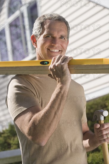 Man holding tools and wood outdoors.