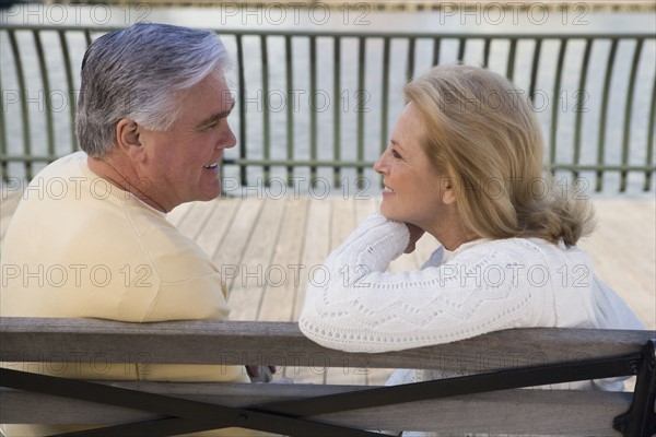 Senior couple sitting on bench outdoors.