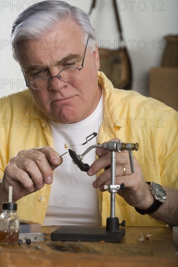 Senior man using soldering iron.