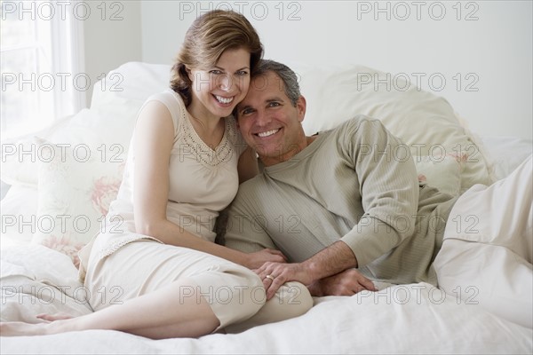 Couple hugging on bed.