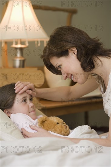 Mother checking young daughter’s temperature.