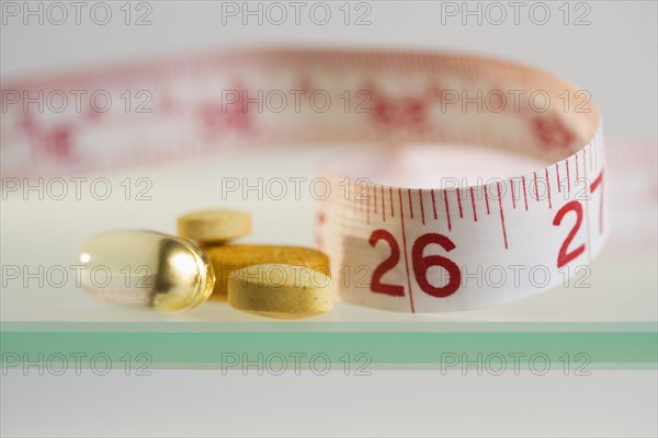 Close up of pills and measuring tape.