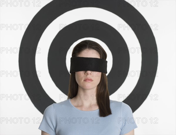 Blindfolded woman standing in front of bull’s eye.