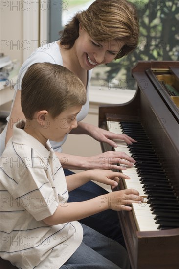 Mother and young son playing piano.