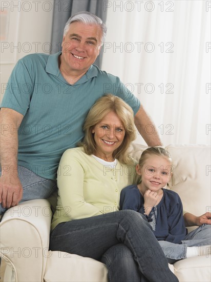 Grandparents and young granddaughter on sofa.