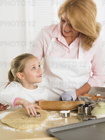 Grandmother and young granddaughter making cookies.
