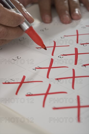 Close up of man crossing out days on calendar.