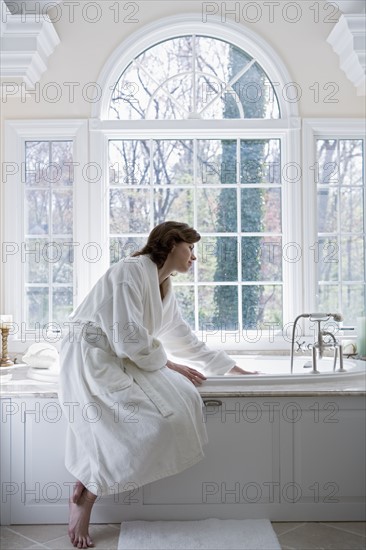 Woman in robe drawing bath.