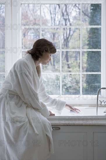 Woman in robe drawing bath.