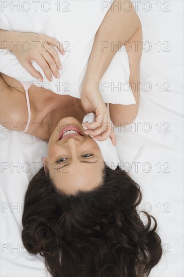 Woman in bed talking on phone.