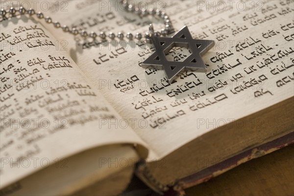 Star of David necklace on book with Hebrew text.