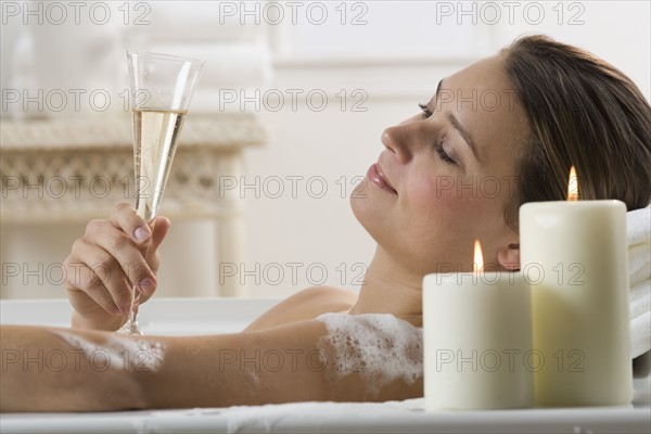 Woman in bathtub with champagne.