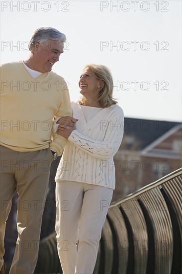 Senior couple walking arm in arm outdoors.
