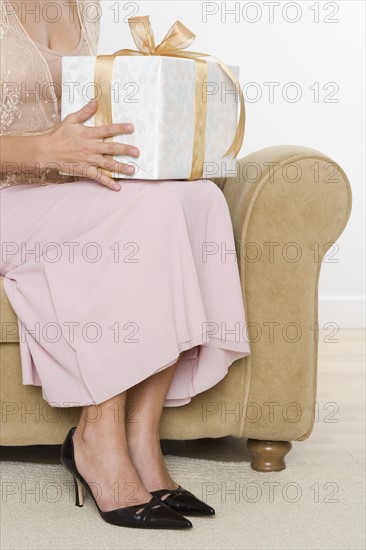 Woman sitting on armchair with gift.