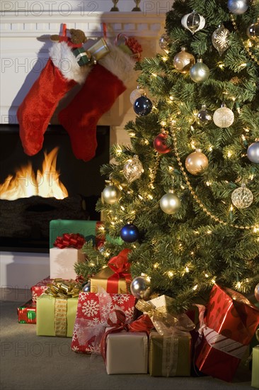 Christmas tree with presents and fireplace with stockings.