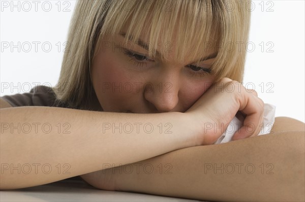 Sad woman with chin resting on her arms.