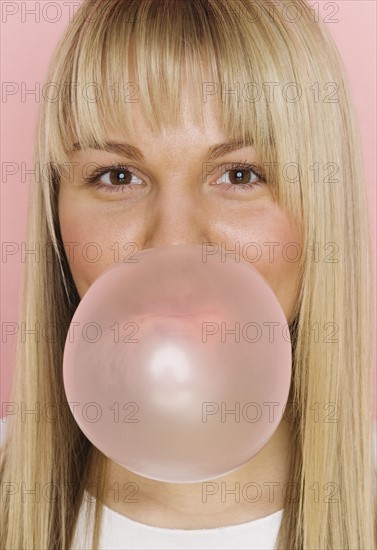 Close up of woman blowing bubble with bubble gum.