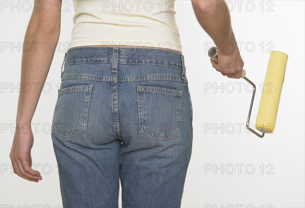 Rear view of woman holding paint roller.