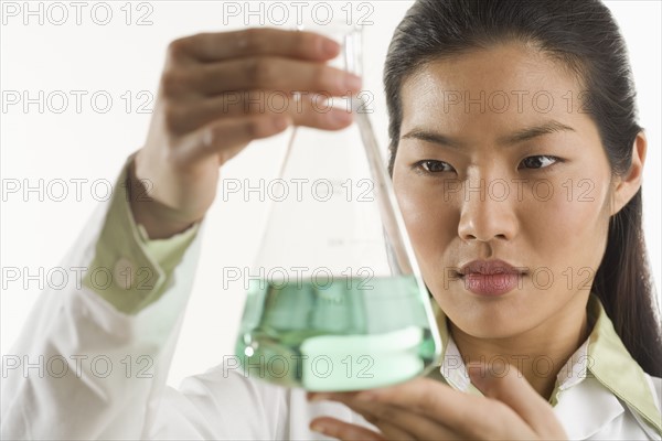 Scientist looking at glass beaker.