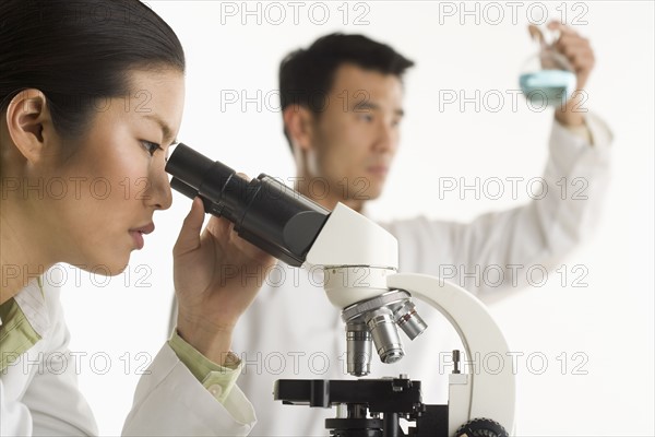 Scientists with beaker and microscope.