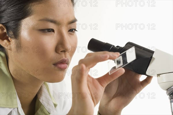 Scientist at microscope looking at slide.