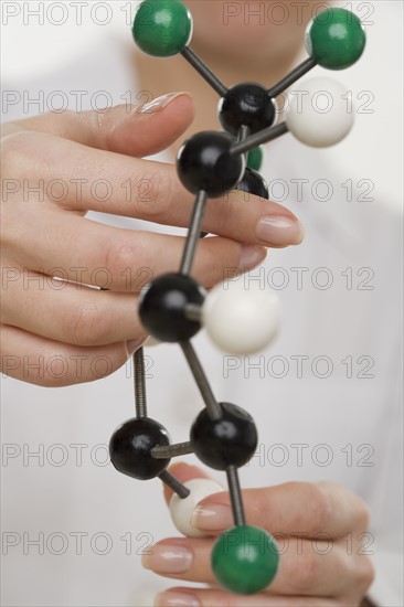 Hands holding molecular model.