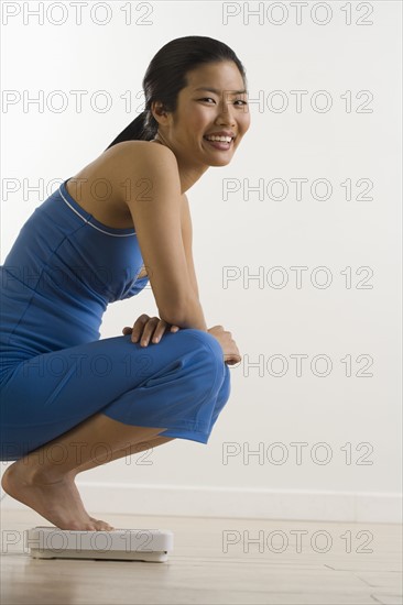 Woman checking weight on scale.