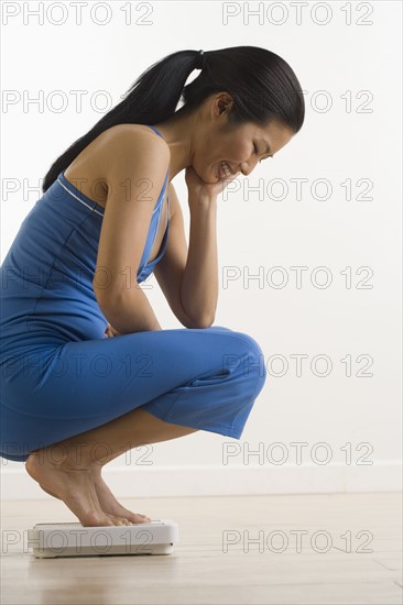 Woman checking weight on scale.