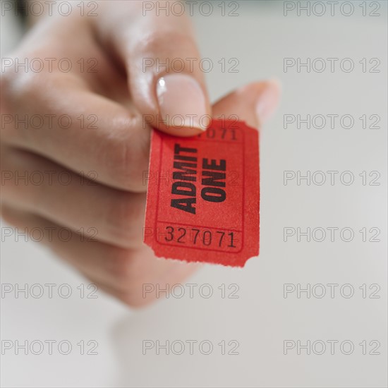 Close up studio shot of woman's hand holding ticket.