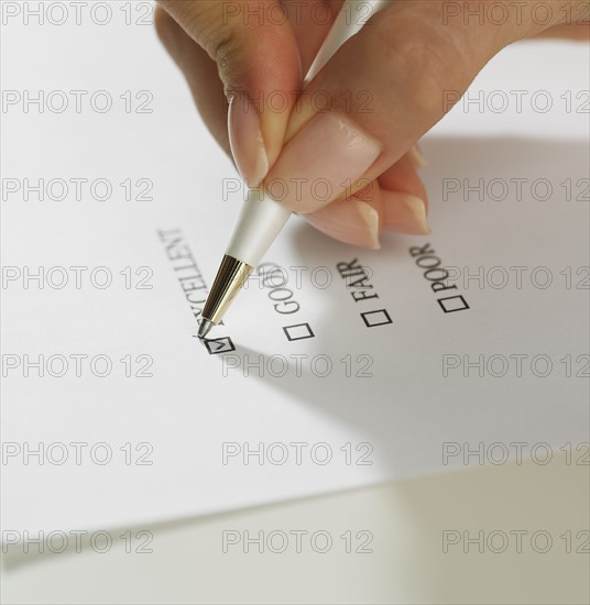 Close up of woman's hand marking check box with pen.