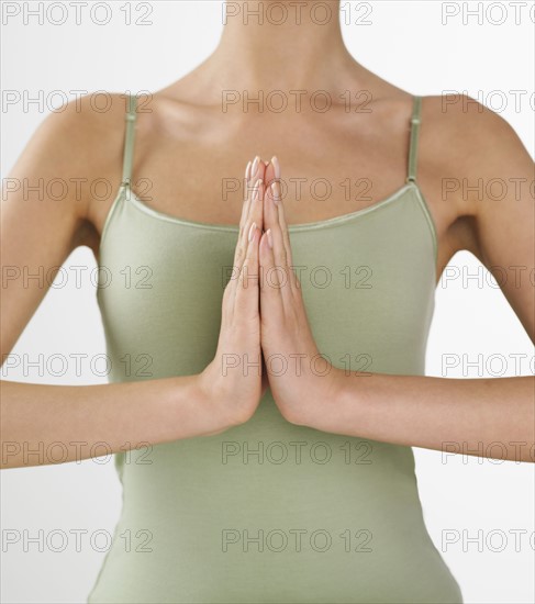 Woman holding palms together in front of heart.