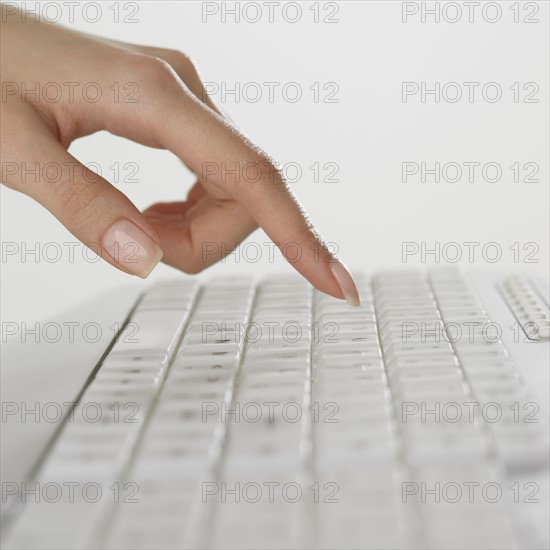 Close up of woman's finger over computer keyboard.