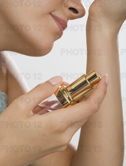 Close up of woman holding perfume and smelling wrist.