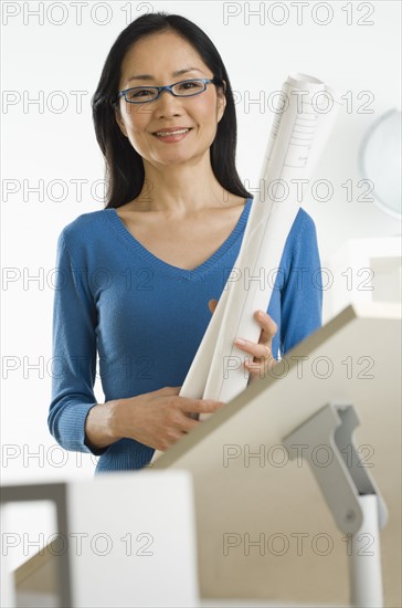 Asian businesswoman holding blueprints.