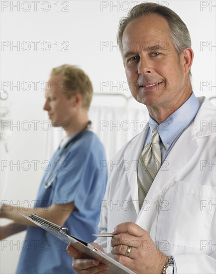 Male doctor smiling and holding chart.