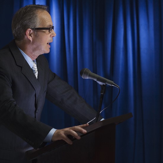 Close up of businessman speaking at podium.