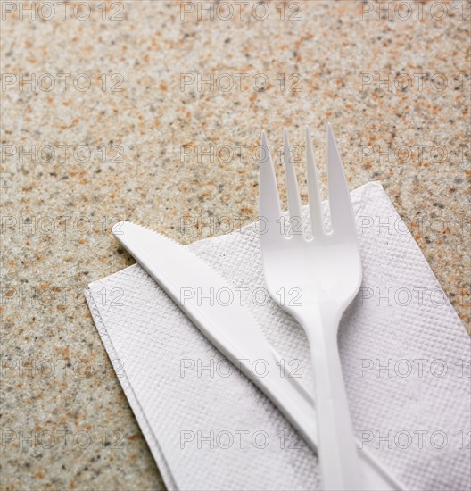 Close up of plastic knife and fork on napkin.
