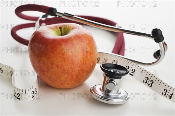 Close up of apple, tape measure and stethoscope.