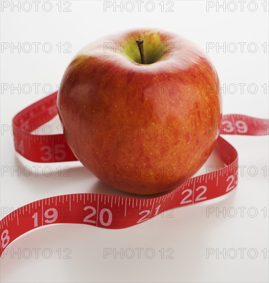 Studio shot of apple and tape measure.