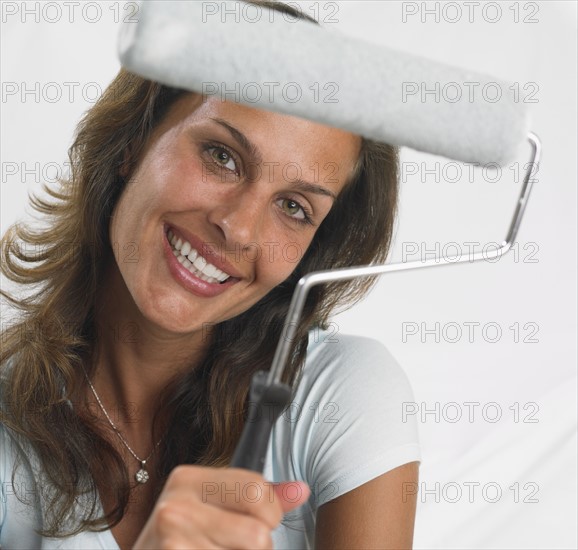 Woman smiling and holding paint roller.