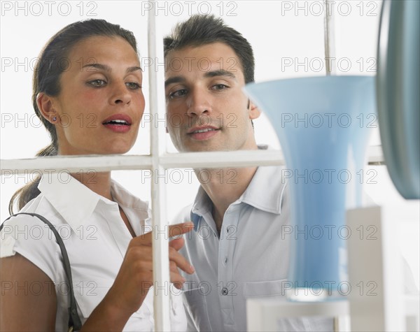 Couple looking through window at vases.