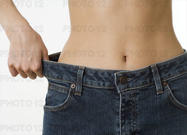 Close up of woman holding waist of pants away from hip.