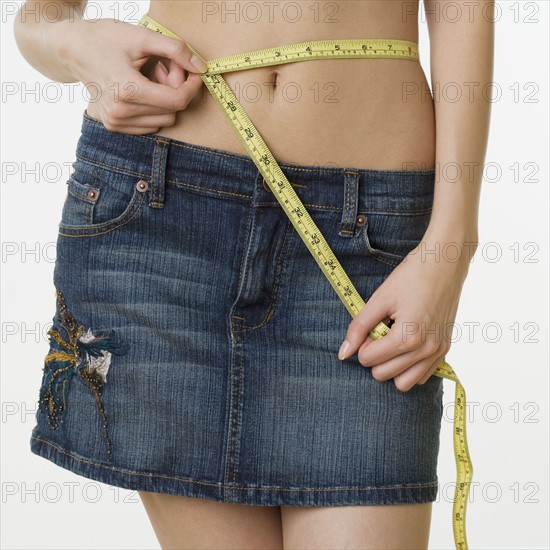 Woman wearing mini skirt and measuring waist.