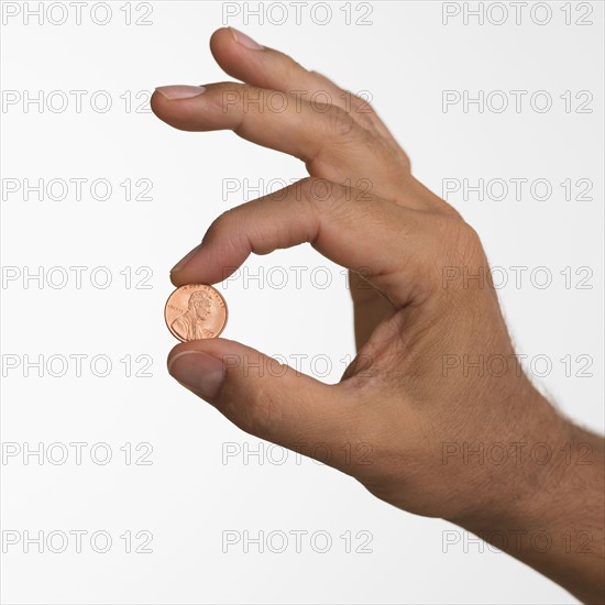 Close up studio shot of man holding penny.