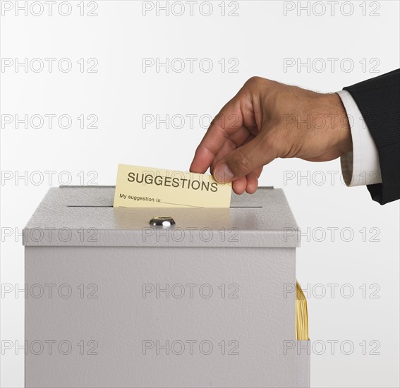 Close up studio shot of man putting card in suggestion box.