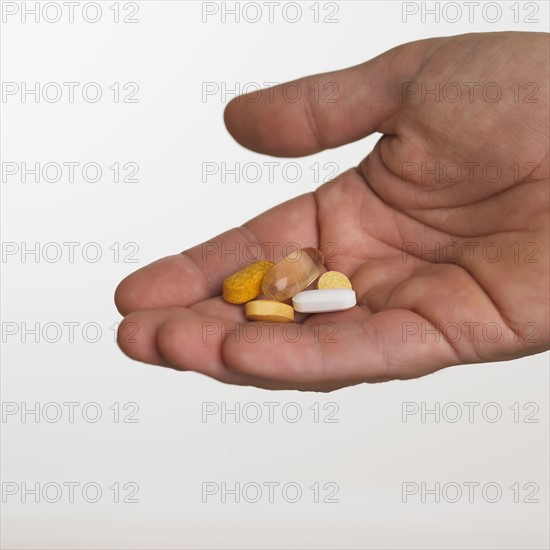 Close up studio shot of man holding vitamins.