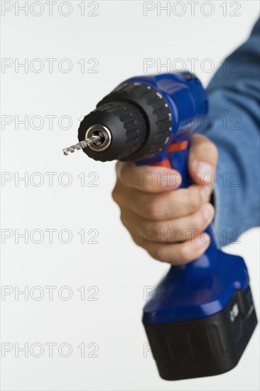 Close up studio shot of man holding cordless drill.