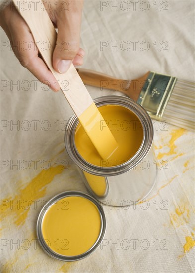 High angle view of man stirring paint in paint can.